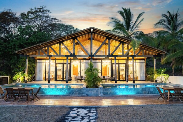 A modern house with a pool, wooden deck, and outdoor seating.