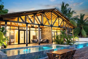 A modern villa with a pool, wooden deck, and stone walls.
