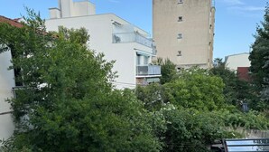 Une terrasse sur le toit dotée d’une balustrade en verre, d’une plateforme en bois et offrant une vue sur les bâtiments et les arbres environnants.