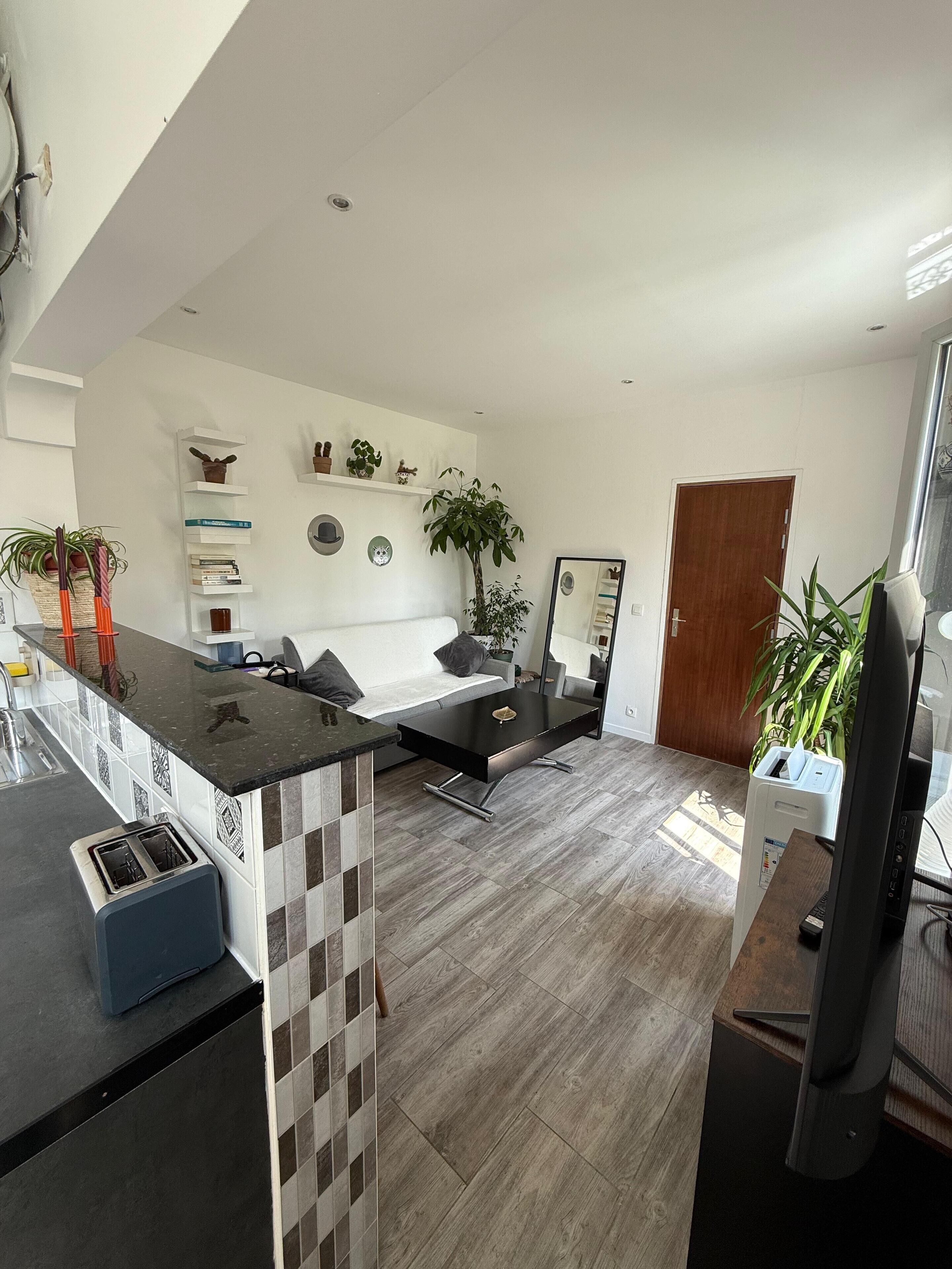 A modern kitchen with a built-in toaster, a dining area with a black table and white chairs, and a living room with a sofa and a coffee table.