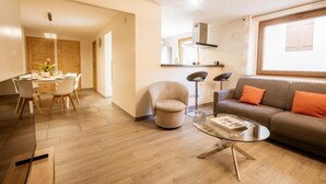 A modern living room with a sofa, a glass coffee table, and a dining area with a table and chairs. - 350m from ski lifts, 1st floor, parking, 67m², Valloire (Valloire)