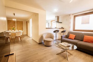 A modern living room with a sofa, a glass coffee table, and a dining area with a table and chairs. - 350m from ski lifts, 1st floor, parking, 67m², Valloire (Valloire)