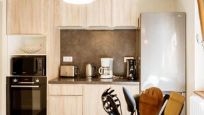 A modern kitchen with wooden cabinets, a microwave, toaster, coffee maker, and a refrigerator. - 350m from ski lifts, 1st floor, parking, 67m², Valloire (Valloire)