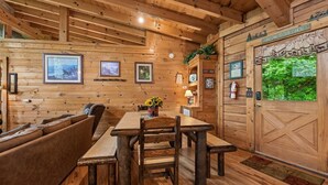 A cabin interior with a wooden dining table, benches, and a sofa.
