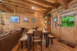 A cabin interior with a wooden dining table, benches, and a sofa.