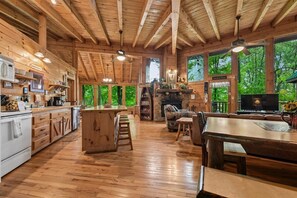 A spacious wooden cabin interior with a kitchen, dining area, and fireplace.