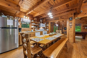 A wooden cabin interior with a kitchen, dining area, and a pool table.