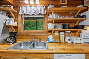 A kitchen with wooden shelves, a double sink, and various kitchen appliances. - Spacious Cabin w/ Pool Table, Hot Tub & Views (Sevierville)