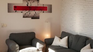 A living room with two grey sofas, a white coffee table, and a red and black abstract painting on the wall. - Sunny apartment, 2 rooms (Looft)