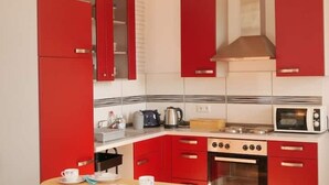 A kitchen with red cabinets, a stove, an oven, and a microwave. - Sunny apartment, 2 rooms (Looft)