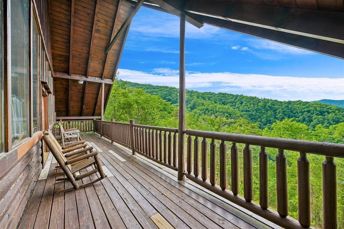 A wooden deck with a view of a forested landscape.
