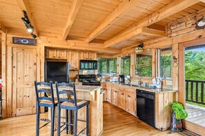 L'intérieur d'un chalet en bois comprend une cuisine, un coin bar et de grandes fenêtres.