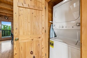Une porte en bois avec une poignée en laiton, un lave-linge blanc doté d’un panneau de commande et un autocollant jaune sur la machine.