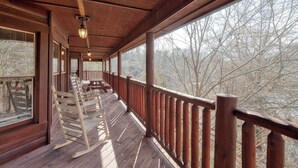 A wooden deck with a railing, benches, and a view of trees. - Mountain Escape w/ Game Room, Hot Tub & Views (Sevierville)