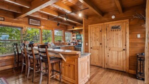 L’intérieur d’un chalet en bois comprend un coin cuisine, des tabourets de bar et une grande porte en bois portant l’inscription « MINDRY ».