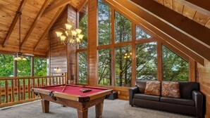 Un intérieur en bois avec une table de billard, un canapé et de grandes fenêtres.