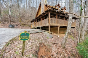 Una cabaña de madera con balcón, rodeada de árboles y un letrero que dice 'Hatfield Hideaway'.