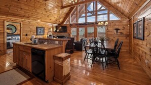 A log cabin interior with a kitchen, dining area, and large windows. - Spacious Lodge w/ Scenic Views & Resort Amenities (Gatlinburg)