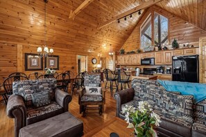 A log cabin interior with a dining area, kitchen, and seating with patterned cushions. - Spacious Lodge w/ Scenic Views & Resort Amenities (Gatlinburg)