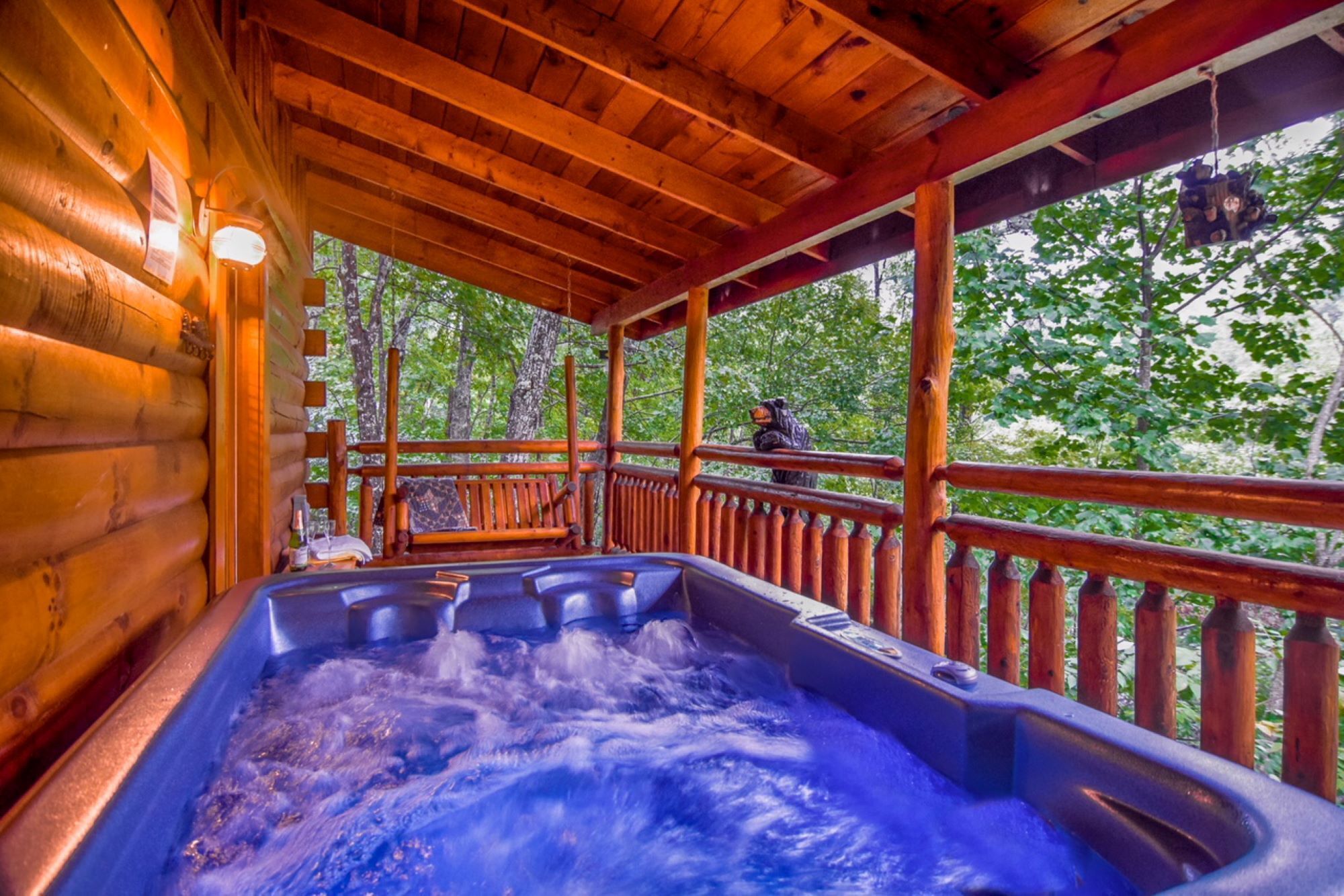 Une cabane en bois dotée d’un bain à remous et d’une terrasse offrant une vue sur une forêt.