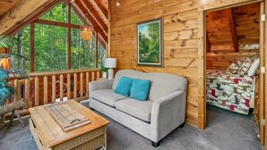 Ein gemütliches Blockhaus-Interieur mit einer Couch, einem kleinen Tisch und einem Fenster mit Blick auf einen Wald.