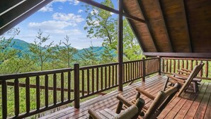 Une terrasse en bois offrant une vue sur des collines verdoyantes et un ciel dégagé.