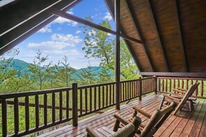 Eine Holzterrasse mit Blick auf grüne Hügel und einen klaren Himmel.