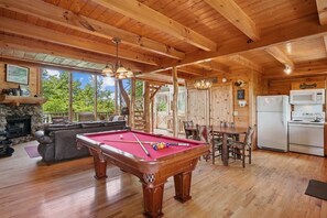 A wooden interior with a pool table, dining table, and kitchen area. - Cozy Cabin with Hot Tub & Scenic Views (Sevierville)
