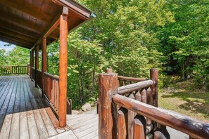 A wooden deck with a railing, surrounded by lush greenery.