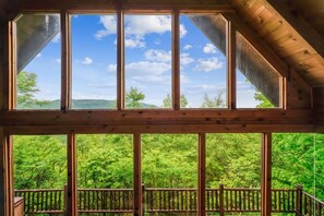 A wooden cabin with large windows offering a view of a forested landscape.