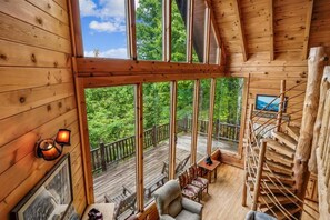 A wooden cabin with a balcony, a fireplace, and a staircase. - Cozy Cabin with Hot Tub & Scenic Views (Sevierville)