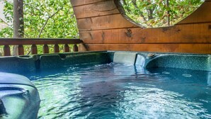 A wooden hot tub with a wooden deck and a view of trees. - Rustic Wooded Cabin w/ Game Room & Hot Tub (Sevierville)