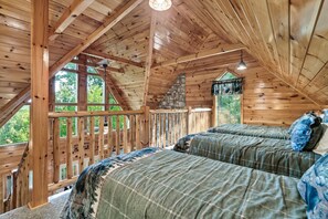 Een houten chalet met een slaapkamer op de entresol, met twee bedden, een stenen openhaard en grote ramen.