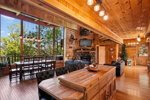 A wooden interior with a dining area, a fireplace, and a television.