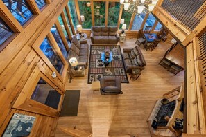 A spacious wooden interior with a central seating area, multiple windows, and a fireplace. - 7-Bedroom Cabin with Game Room & Hot Tub (Sevierville)