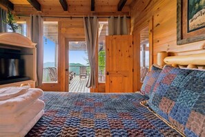 A cozy cabin room with a bed, a television, and a view of the outdoors. - 7-Bedroom Cabin with Game Room & Hot Tub (Sevierville)