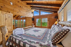 A wooden cabin bedroom with a bed, a ceiling fan, and a window with blinds. - 7-Bedroom Cabin with Game Room & Hot Tub (Sevierville)