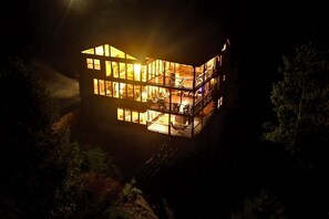A multi-story building with large windows and balconies, surrounded by trees. - 7-Bedroom Cabin with Game Room & Hot Tub (Sevierville)