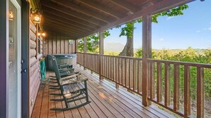 Eine Holzterrasse mit Schaukelstühlen, einem Whirlpool und Blick auf eine Berglandschaft.