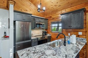 A modern kitchen with granite countertops, stainless steel appliances, and wooden paneling.