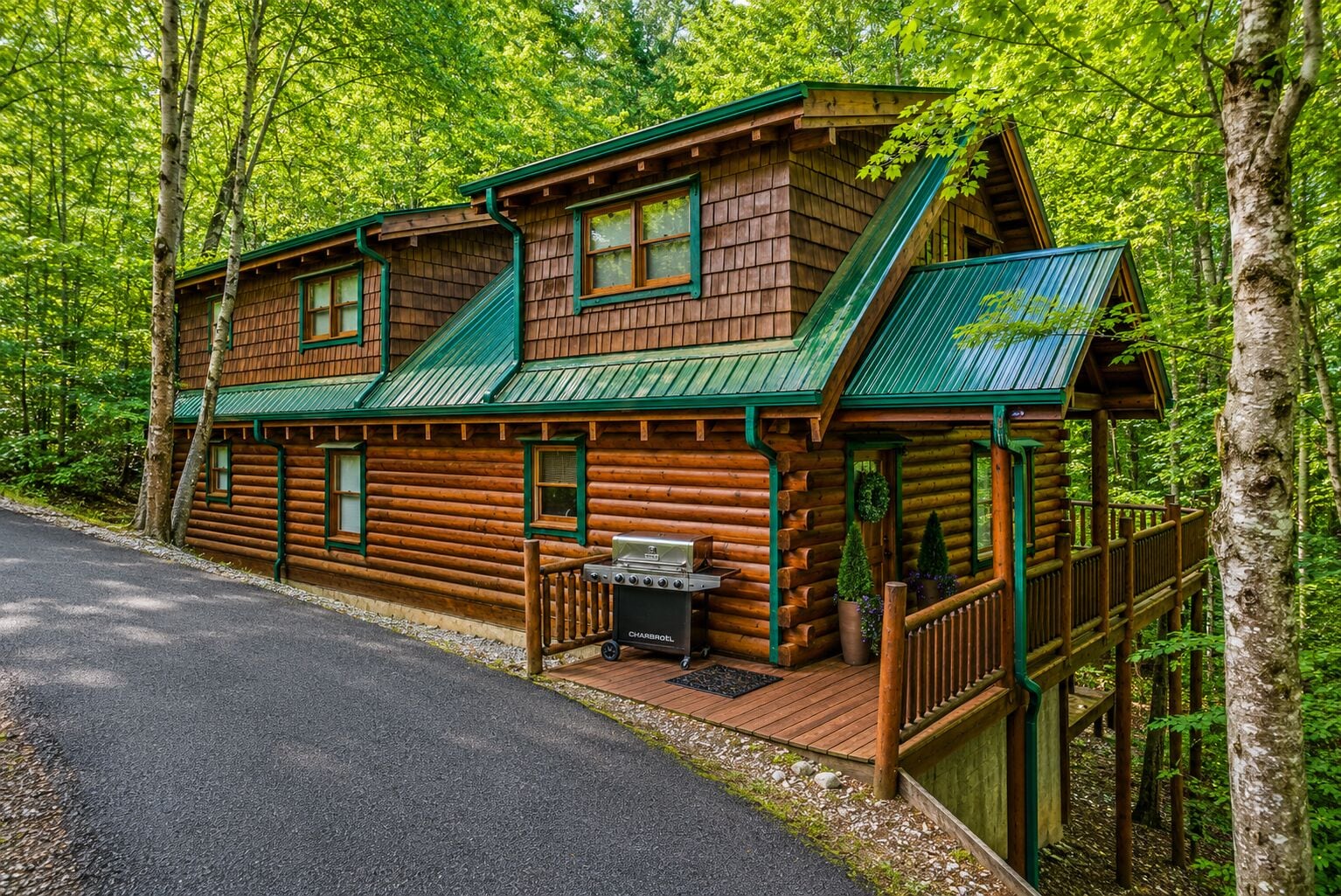 Une cabane en rondins avec une terrasse, un barbecue et un porche abrité.