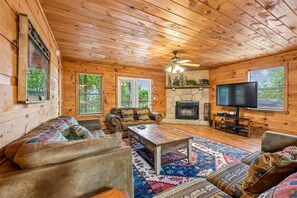 Ein Blockhaus-Interieur mit Kamin, Fernseher und einem großen Teppich.