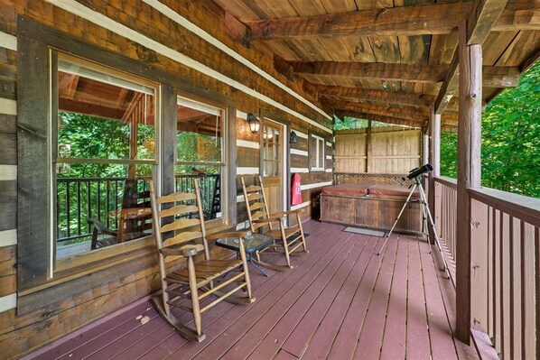 A wooden deck with rocking chairs and a hot tub. - Rustic Charm & Comfort w/ Hot Tub & Views (Sevierville)
