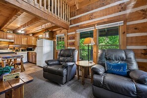A cabin interior with a kitchen, dining area, and seating with a view.