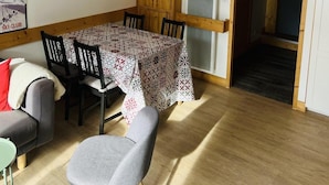 A dining area with a wooden table and chairs, a sofa, and a small table with a chair. - 250m from ski slopes, 1st floor, terrace, parking, ski locker, 60m², Valloire (Valloire)