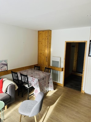 Ein Essbereich mit Holztisch und Stühlen, einer Couch und einem kleinen Tisch mit einem Sessel.