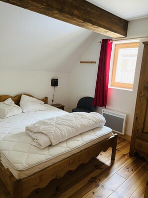 Ein Schlafzimmer mit einem hölzernen Bett, einem roten Vorhang, einem Heizkörper und einem Fenster mit Blick.