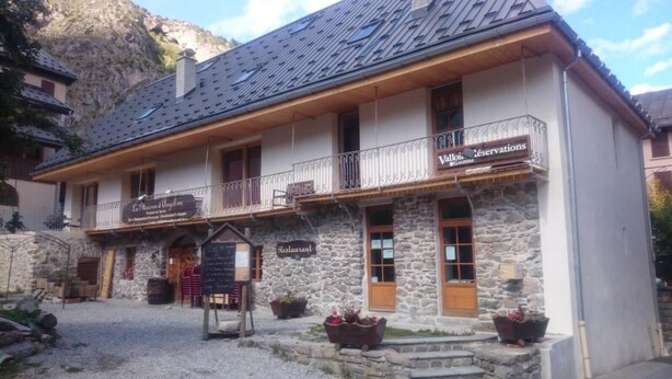 A stone building with a balcony, a sign for "Valloir Reservations," and a sign for "La Maison d'Auverne." - 250m from ski slopes, 1st floor, terrace, parking, ski locker, 60m², Valloire (Valloire)