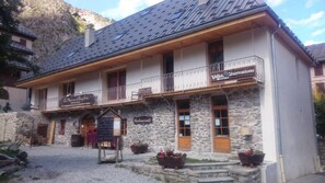 A stone building with a balcony, a sign for "Valloir Reservations," and a sign for "La Maison d'Auverne." - 250m from ski slopes, 1st floor, terrace, parking, ski locker, 60m², Valloire (Valloire)