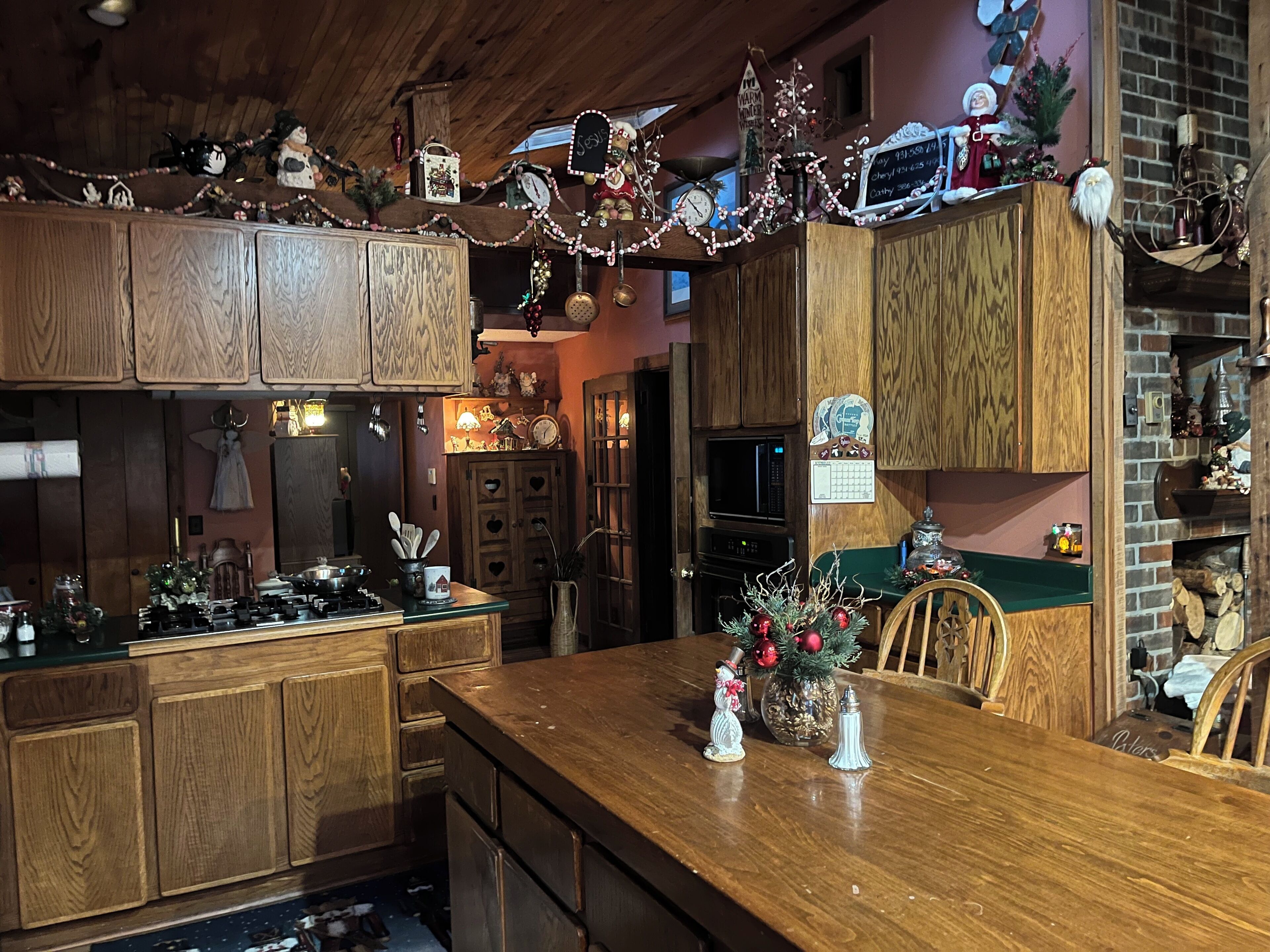 A kitchen with wooden cabinets, a wooden countertop, and various kitchen appliances. There are decorations on the ceiling and a small Christmas tree on the countertop.